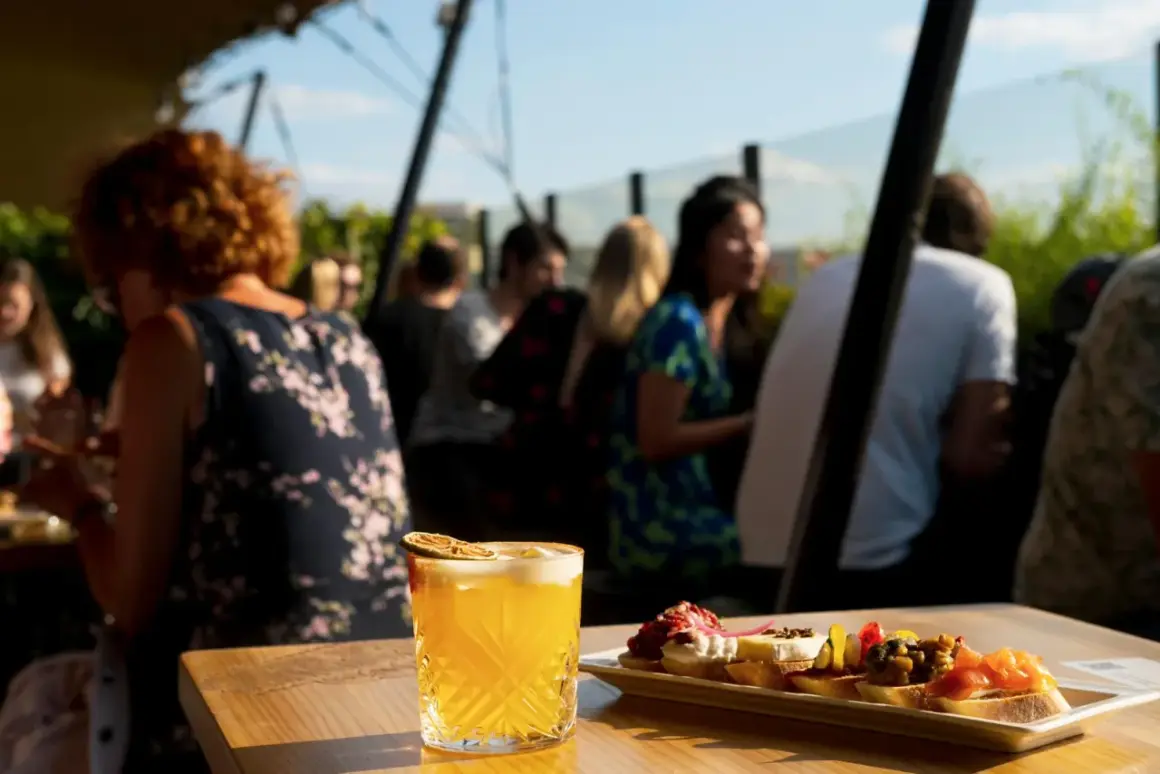 Cocktail et tapas sur une terrasse de toit à Paris, avec des gens en arrière-plan.