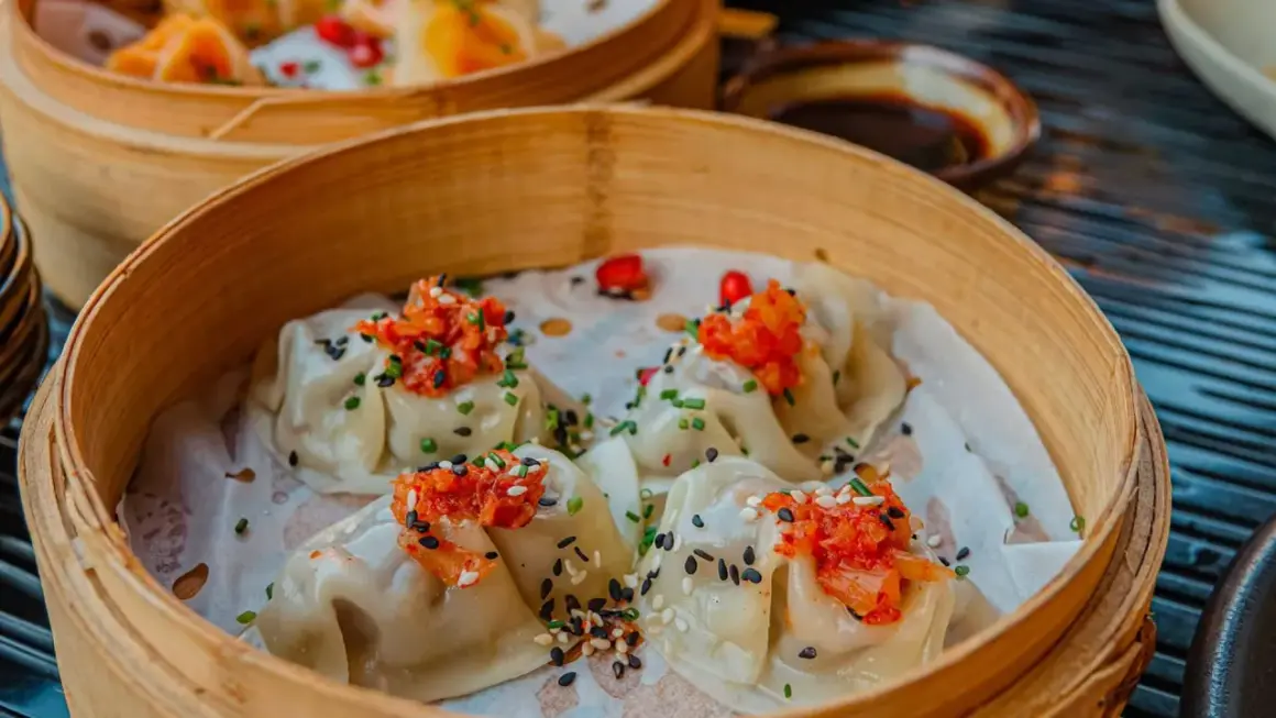 Délicieux dim sum à Paris, servis dans un panier en bambou, garnis de garnitures vibrantes et de graines de sésame.