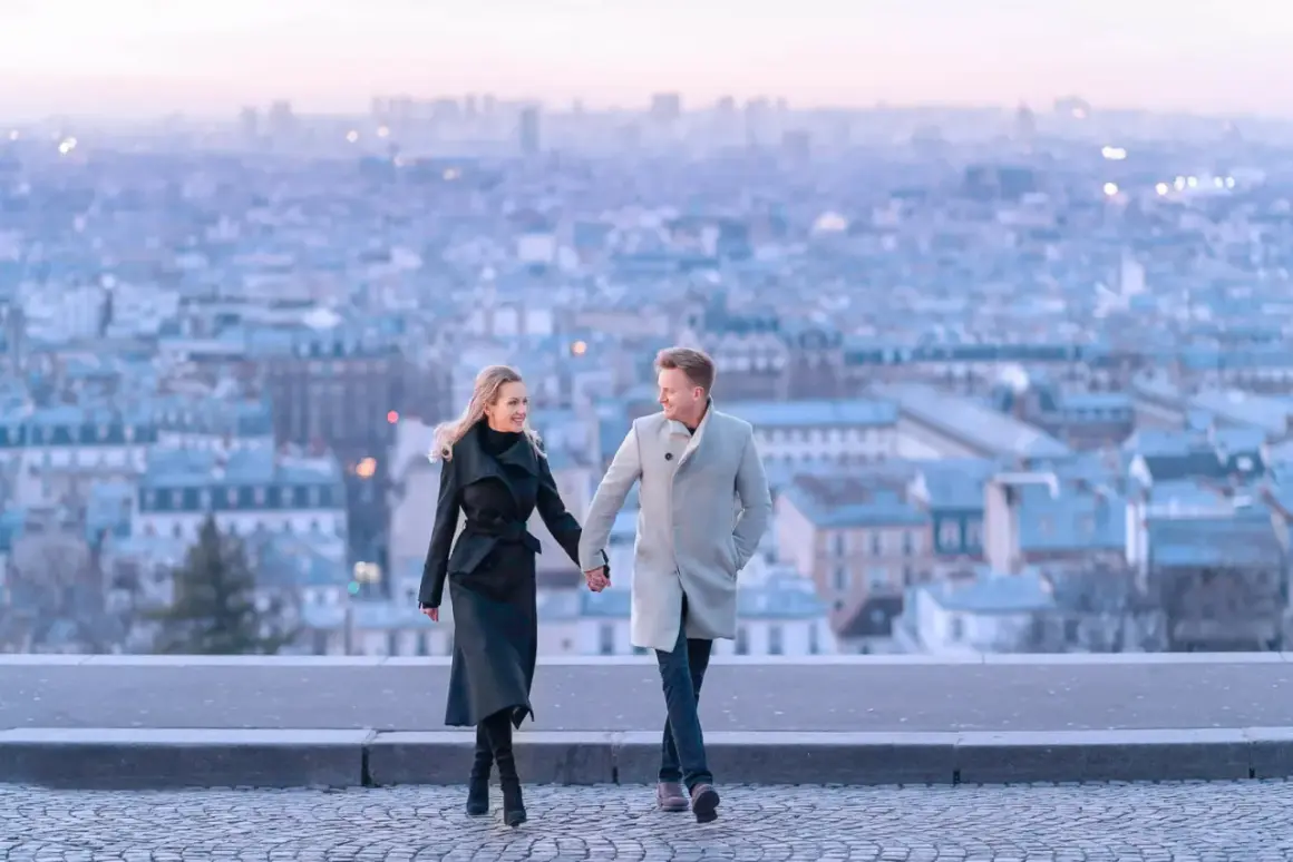 Un couple se promène main dans la main, avec Paris en arrière-plan. Un spot photo parisien parfait pour immortaliser un moment romantique.