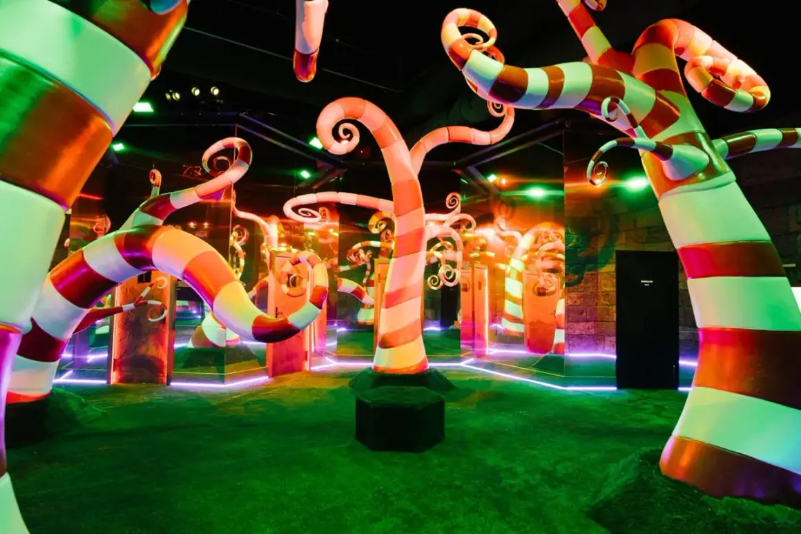 Un décor féerique avec des arbres en bonbons rayés, des miroirs et des lumières néon, typique d'un musée interactif à Paris.