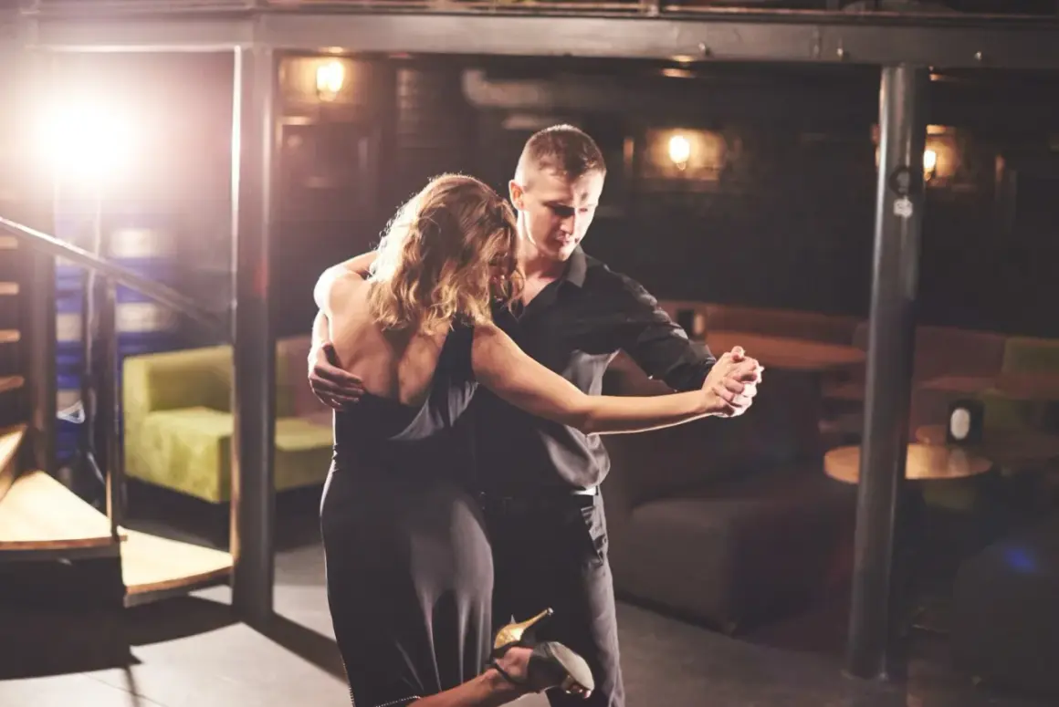 Un couple danse passionnément lors d'une soirée dansante à Paris. L'homme en chemise noire enlace la femme en robe de soirée.