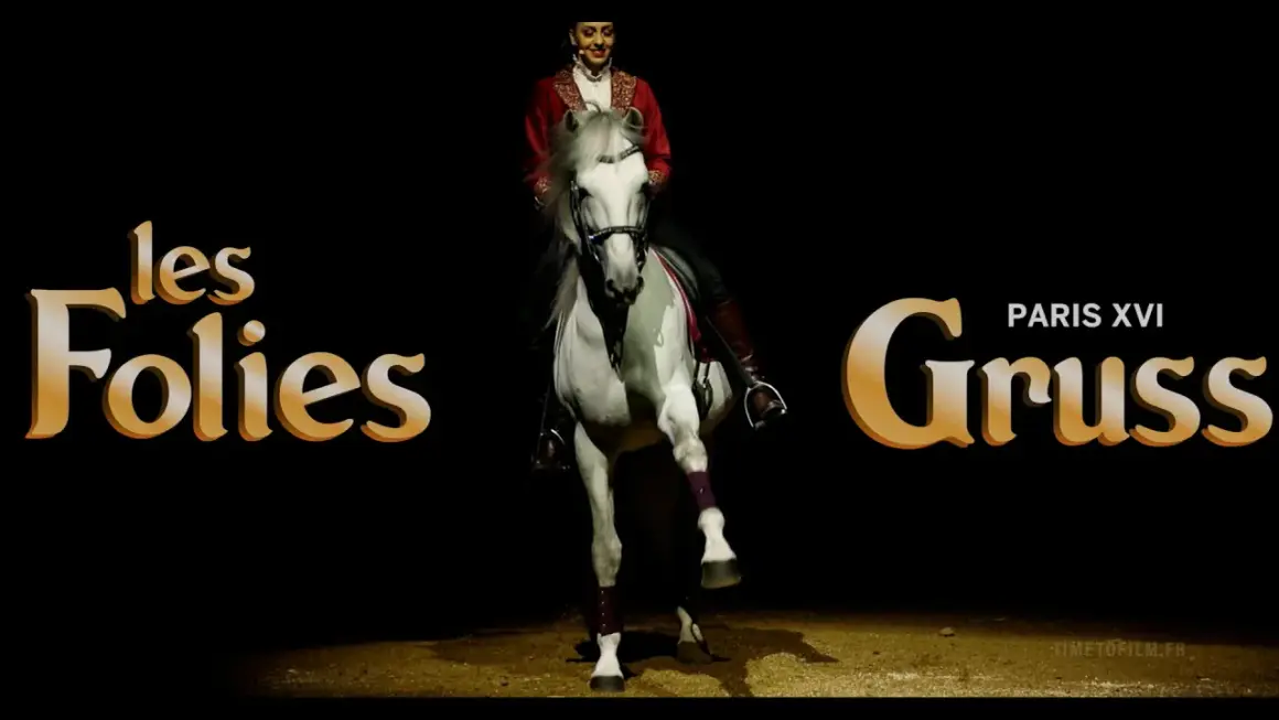 Une écuyère en tenue rouge sublime un cheval blanc lors d'un spectacle des Folies Gruss.