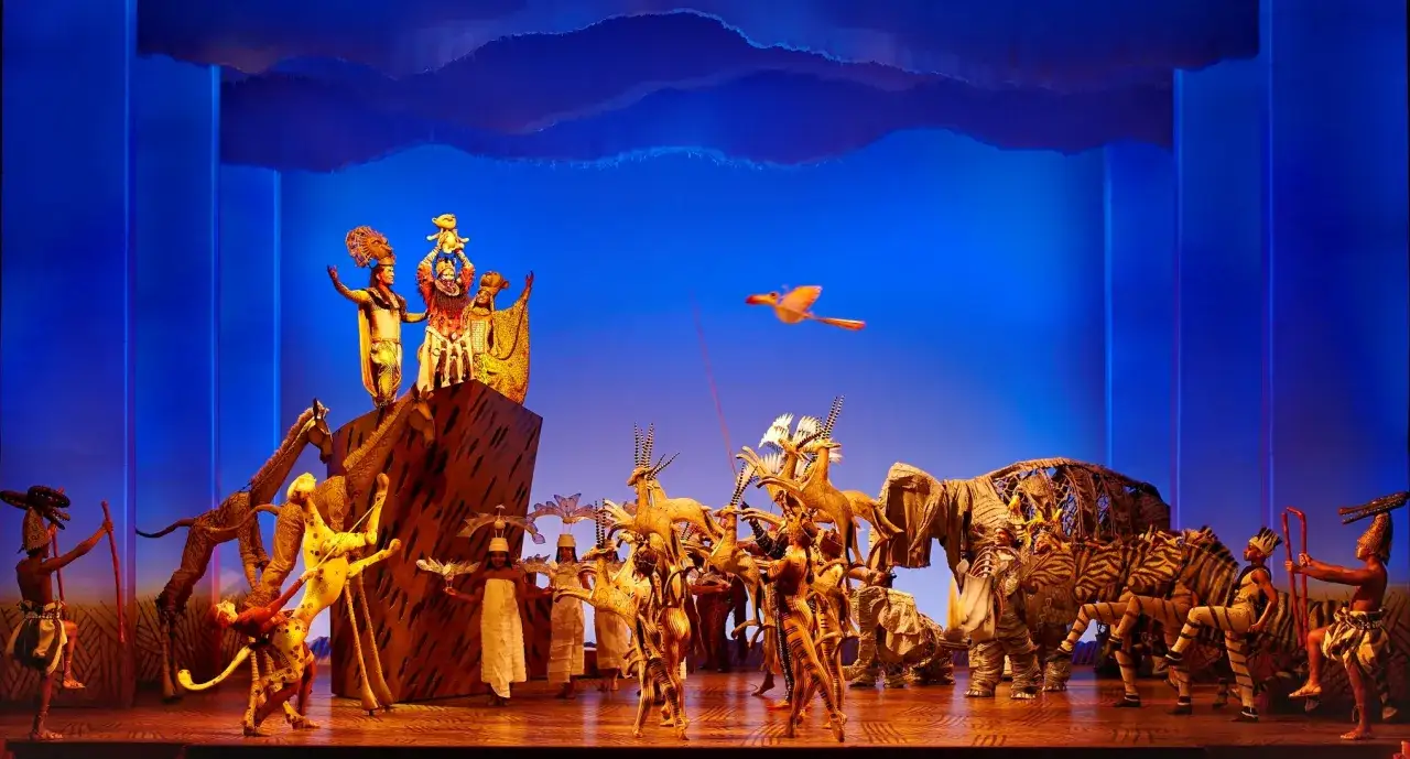 La scène du Roi Lion Mogador s'anime : Rafiki présente Simba, entouré d'animaux magnifiques et de danseurs.