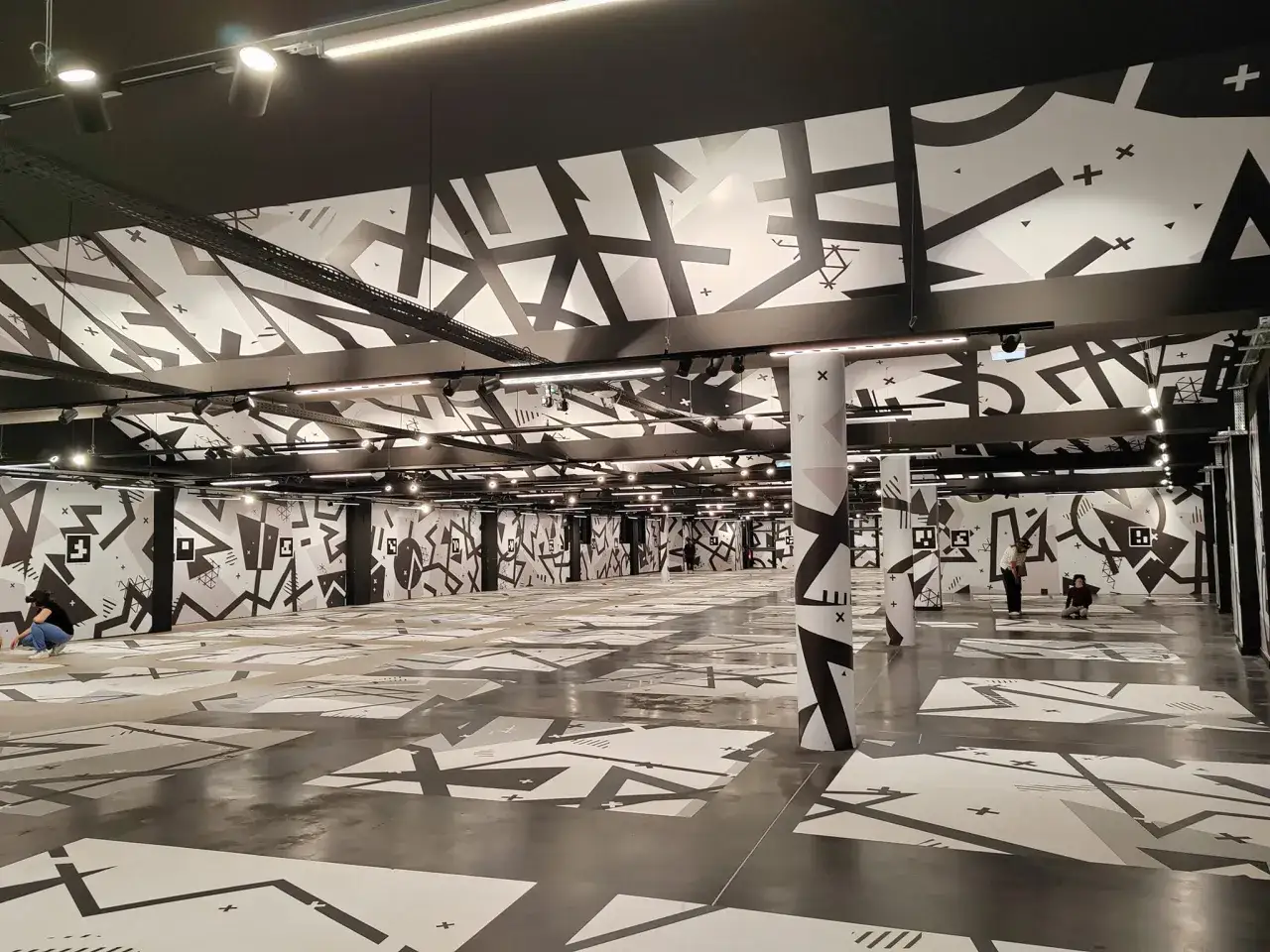 Immersion dans une installation artistique monumentale à Eclipso Paris, où des motifs graphiques noirs et blancs recouvrent murs, sol et plafond.