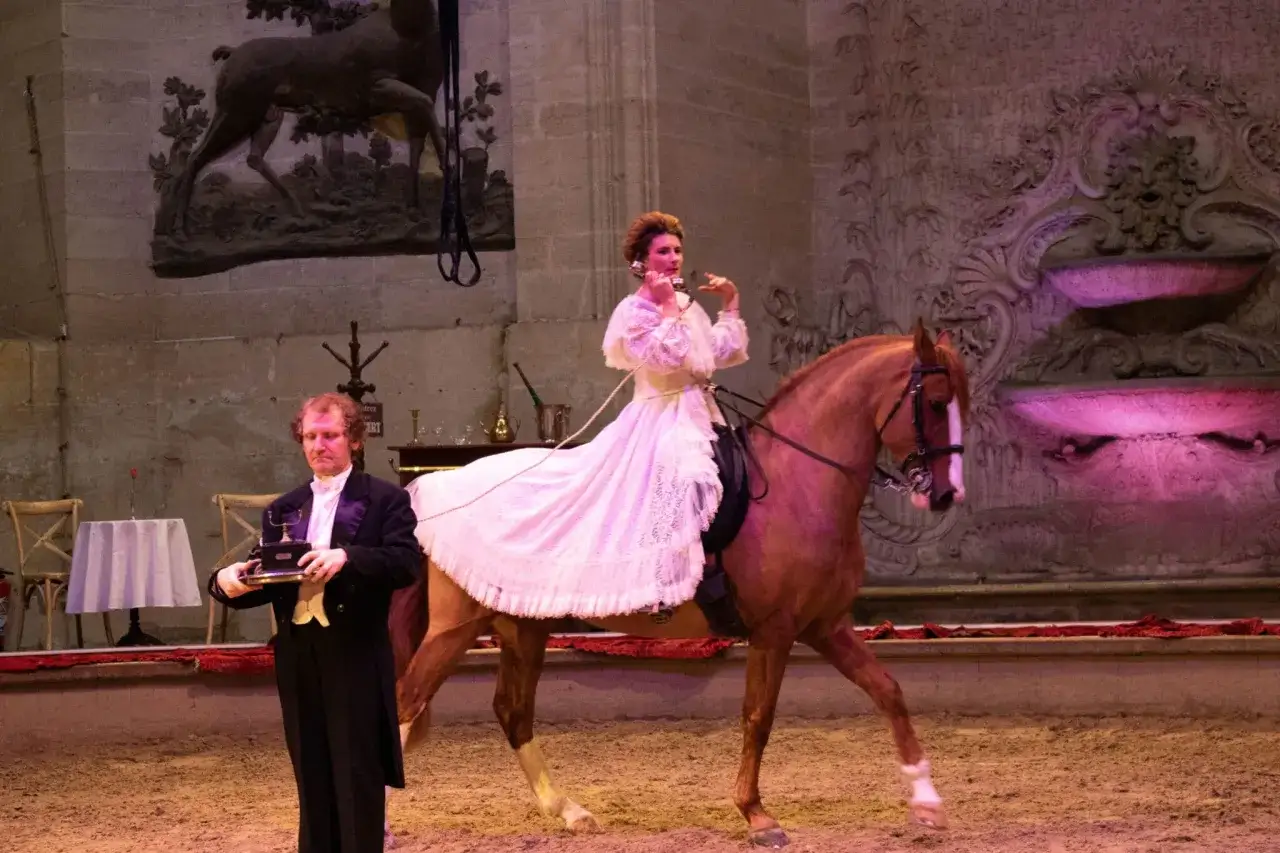 Une femme en robe blanche sur un cheval, au t&eacute;l&eacute;phone, et un homme en costume tenant un phonographe, sc&egrave;ne des folies gruss.