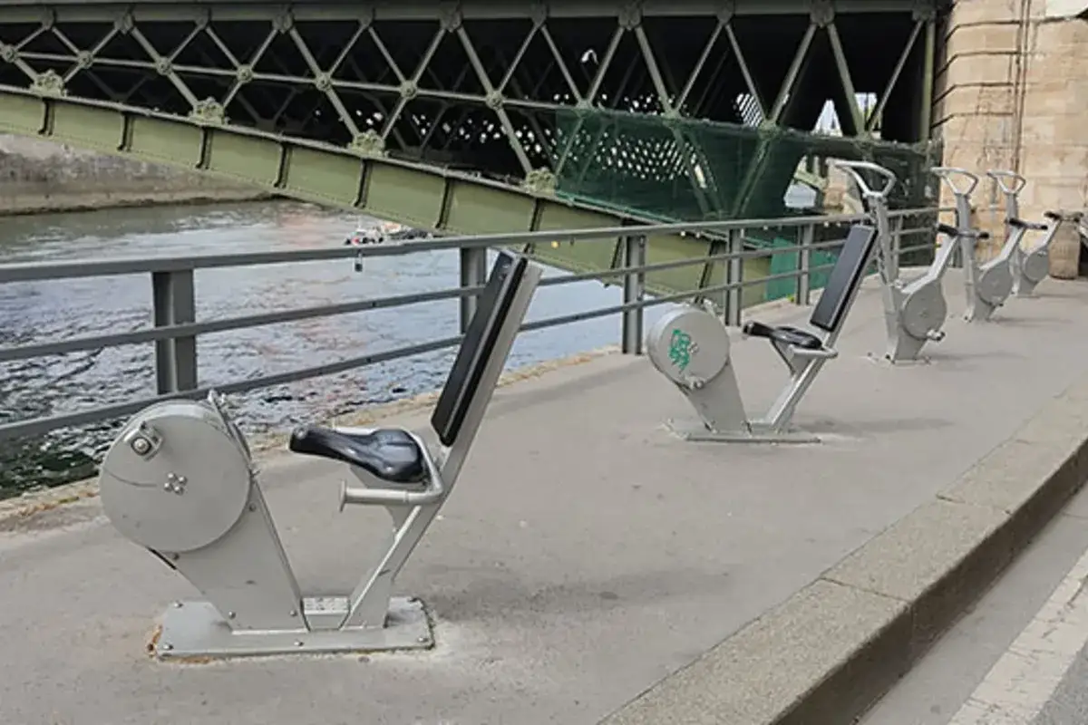 Appareils de musculation en plein air le long de la Seine, offrant une activit&eacute; sportive &agrave; Paris sous un pont vert.