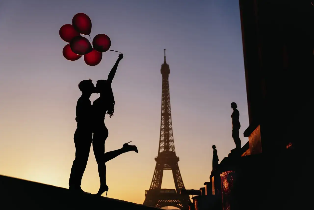 Silhouette d'un couple s'embrassant avec des ballons rouges devant la Tour Eiffel. Une id&eacute;e date Paris parfaite pour une soir&eacute;e romantique.