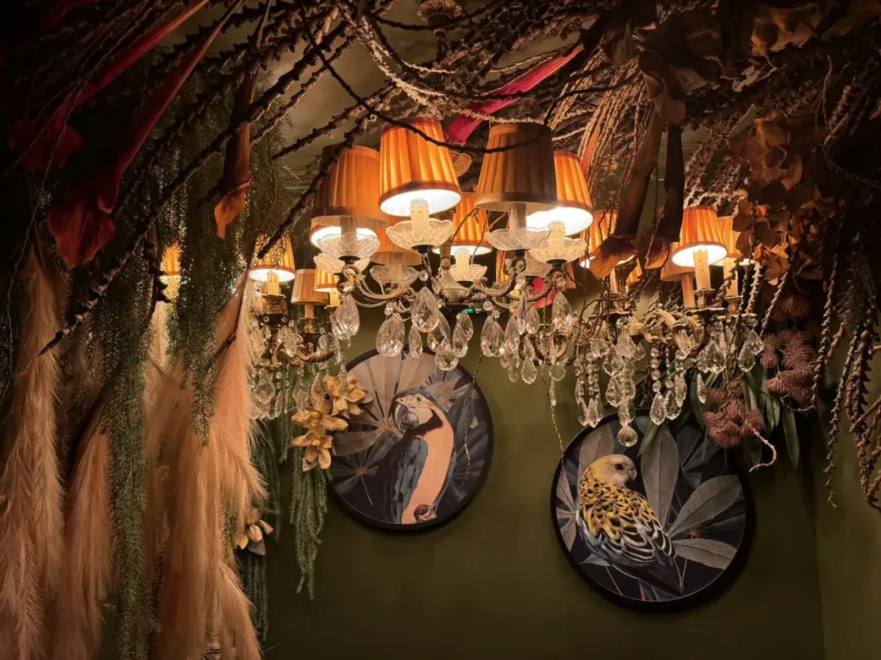 Lustre baroque et tableaux d'oiseaux dans un restaurant insolite &agrave; Paris, ambiance jungle luxuriante.