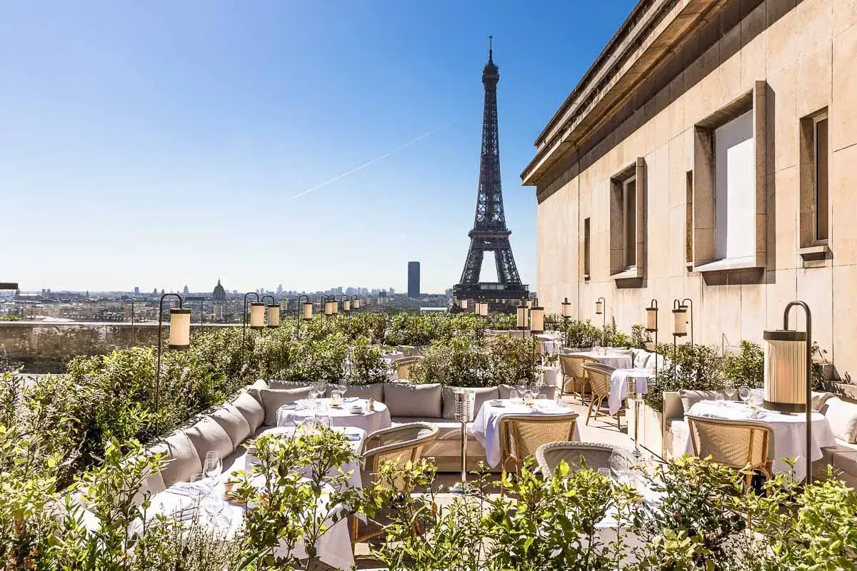 Magnifique terrasse pour un brunch rooftop &agrave; Paris, avec la Tour Eiffel en toile de fond. Tables dress&eacute;es, v&eacute;g&eacute;tation luxuriante et vue imprenable.