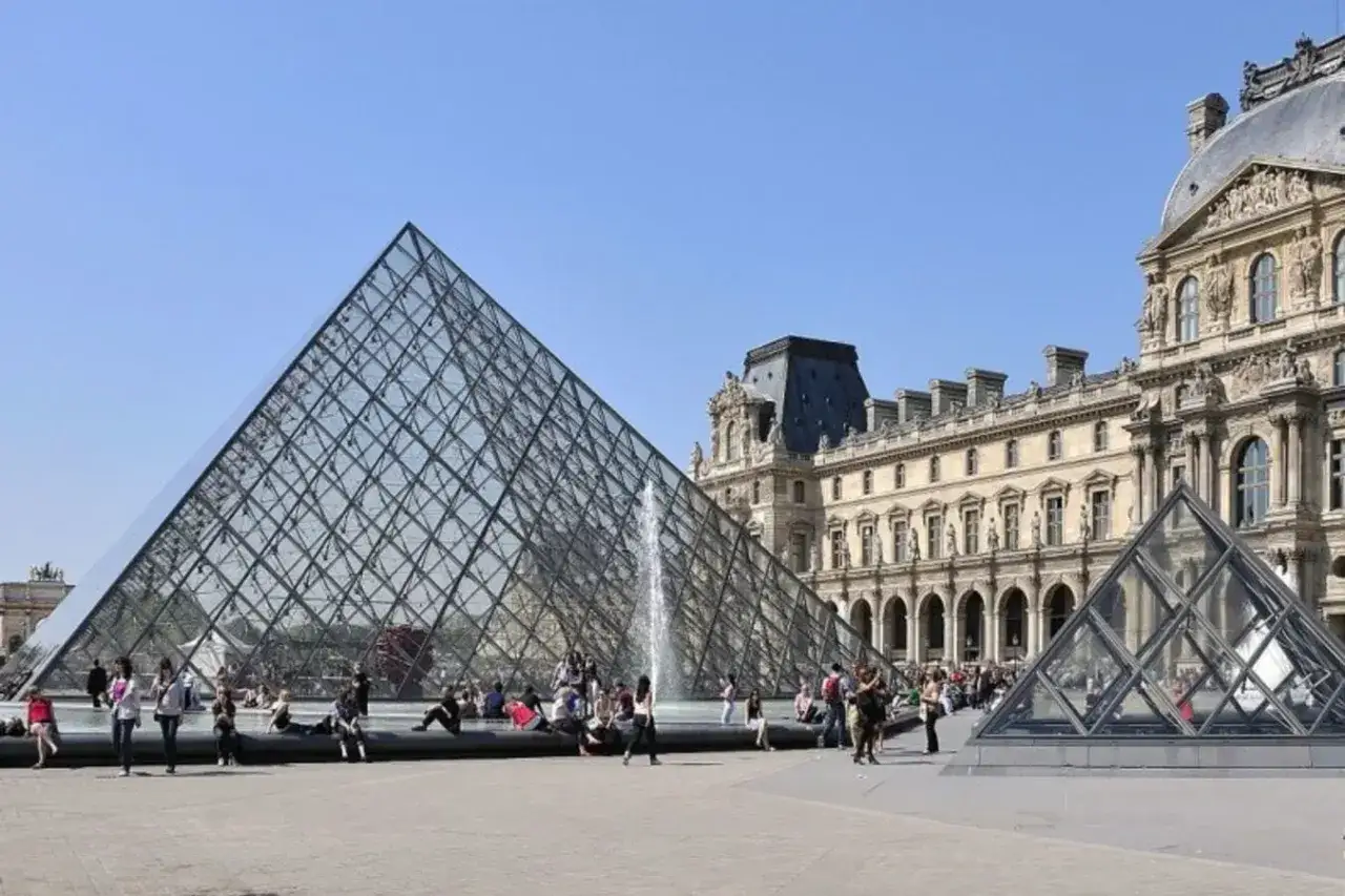 La pyramide du Louvre, un des mus&eacute;es ouverts le lundi, attire des visiteurs sous un ciel bleu.