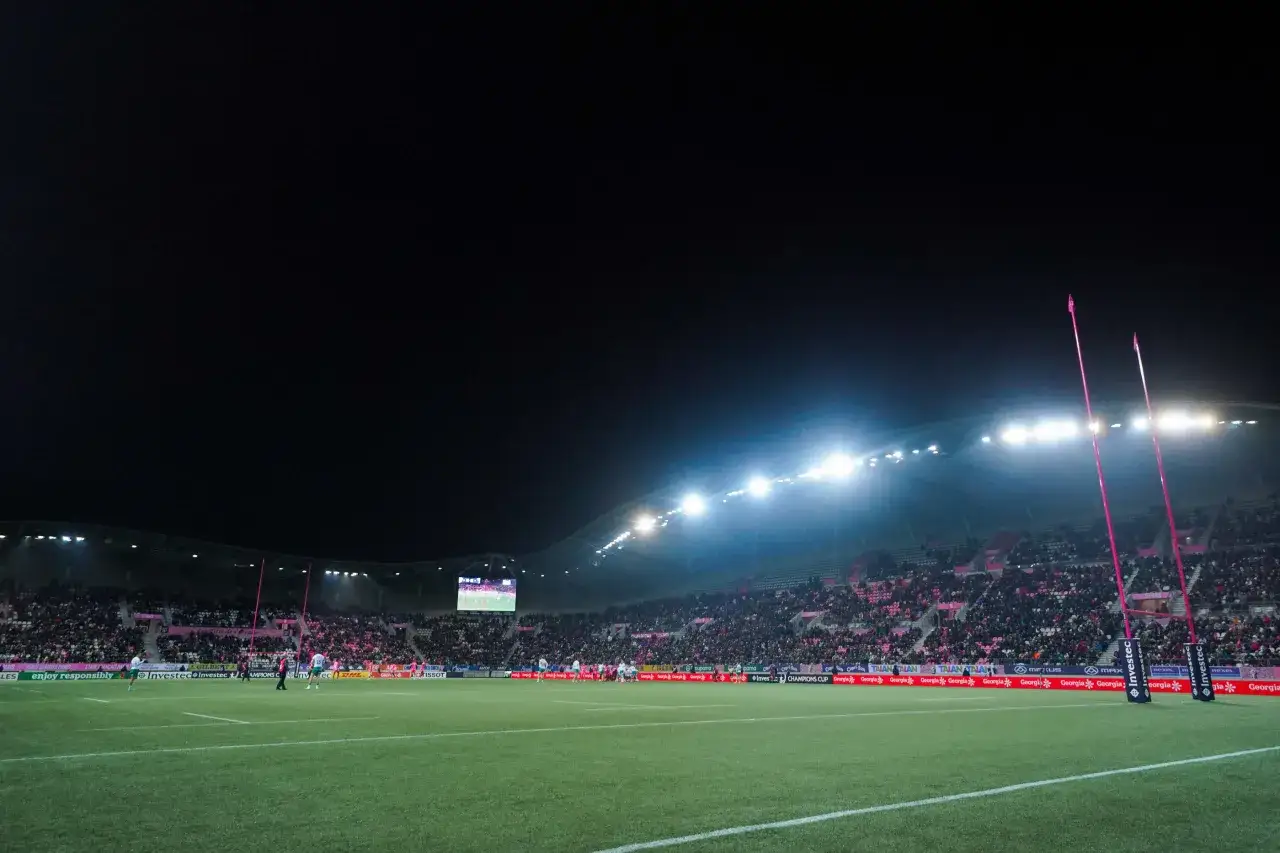 Le stade Jean Bouin s'illumine pour un match de rugby, les poteaux roses se dressent sous les projecteurs, les tribunes sont pleines.