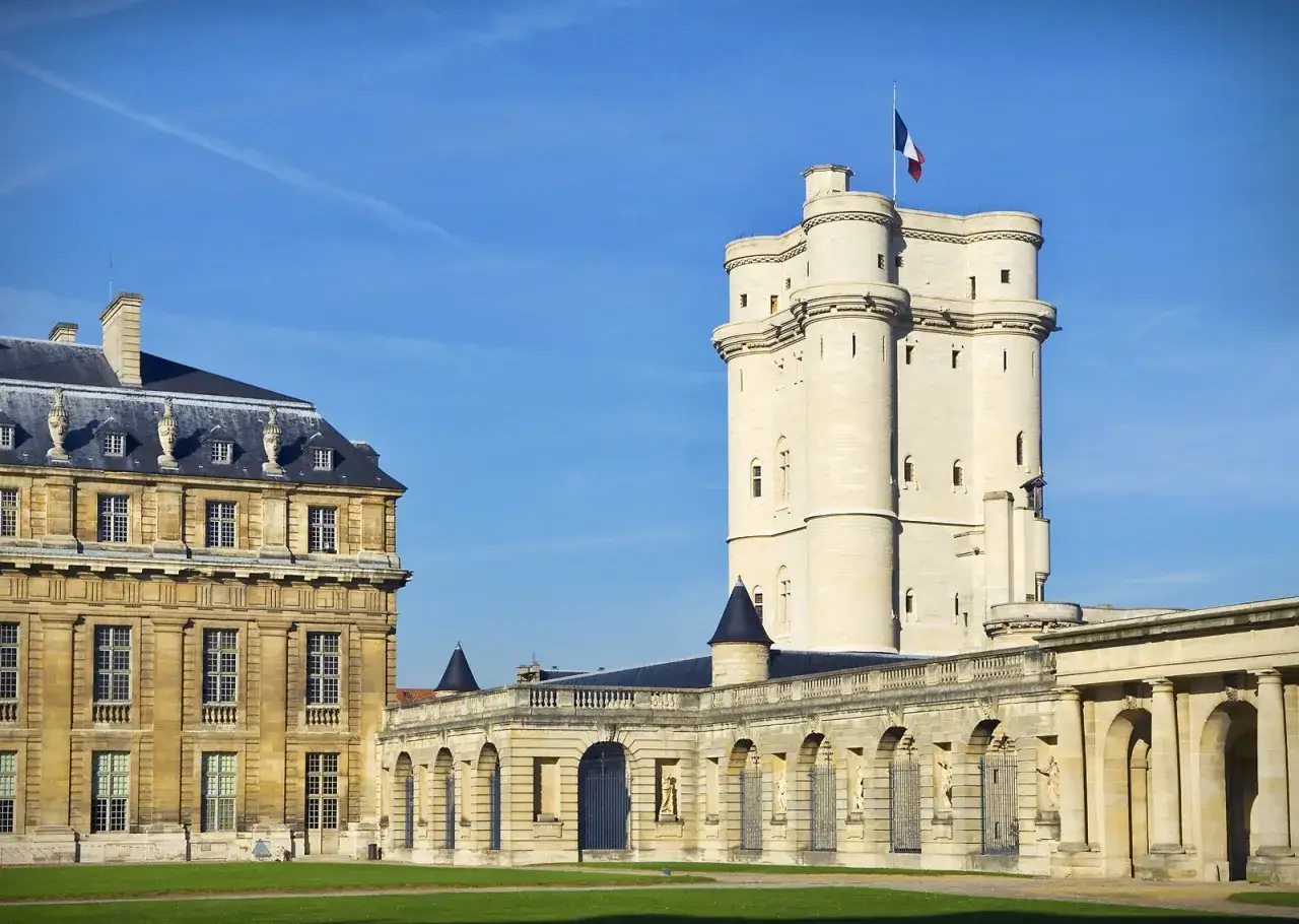 Le ch&acirc;teau de Vincennes se dresse fi&egrave;rement sous un ciel bleu, avec sa tour imposante et ses b&acirc;timents historiques.