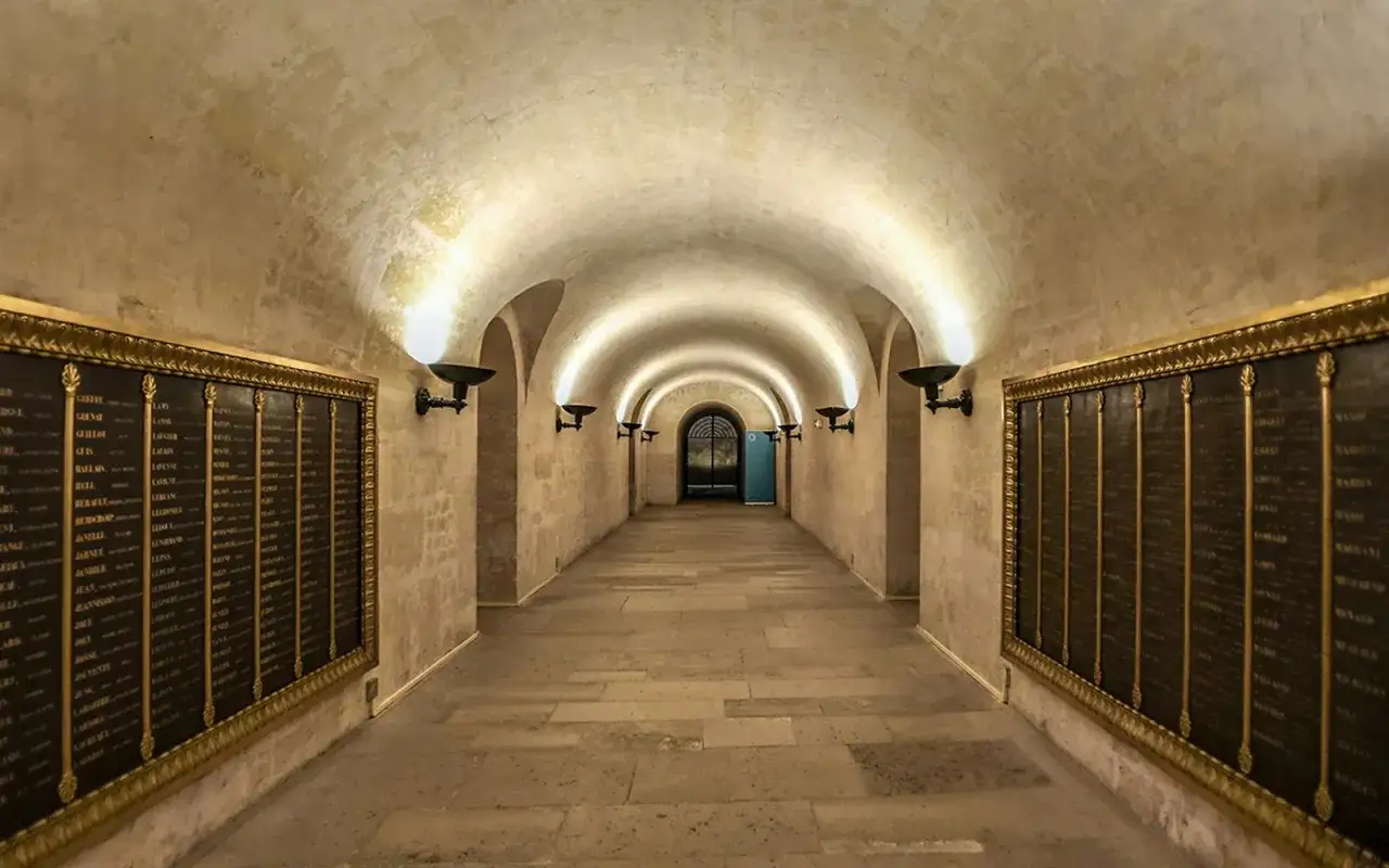 Couloir vo&ucirc;t&eacute; du Panth&eacute;on de Paris, &eacute;clair&eacute; par des appliques murales, avec des plaques comm&eacute;moratives sur les murs.