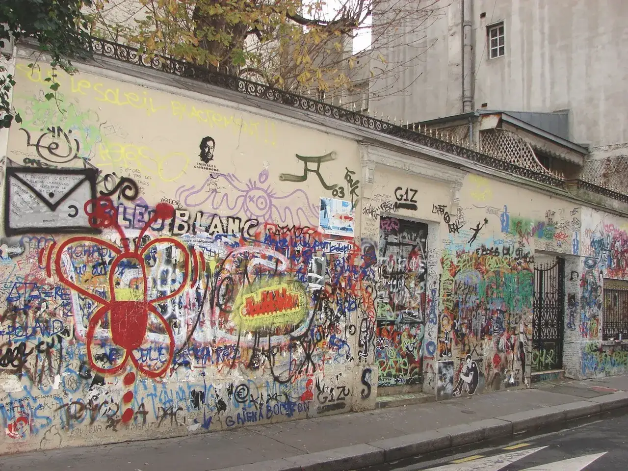 Le mur de la maison Gainsbourg, couvert de graffitis color&eacute;s, dont un grand papillon rouge et des portraits.