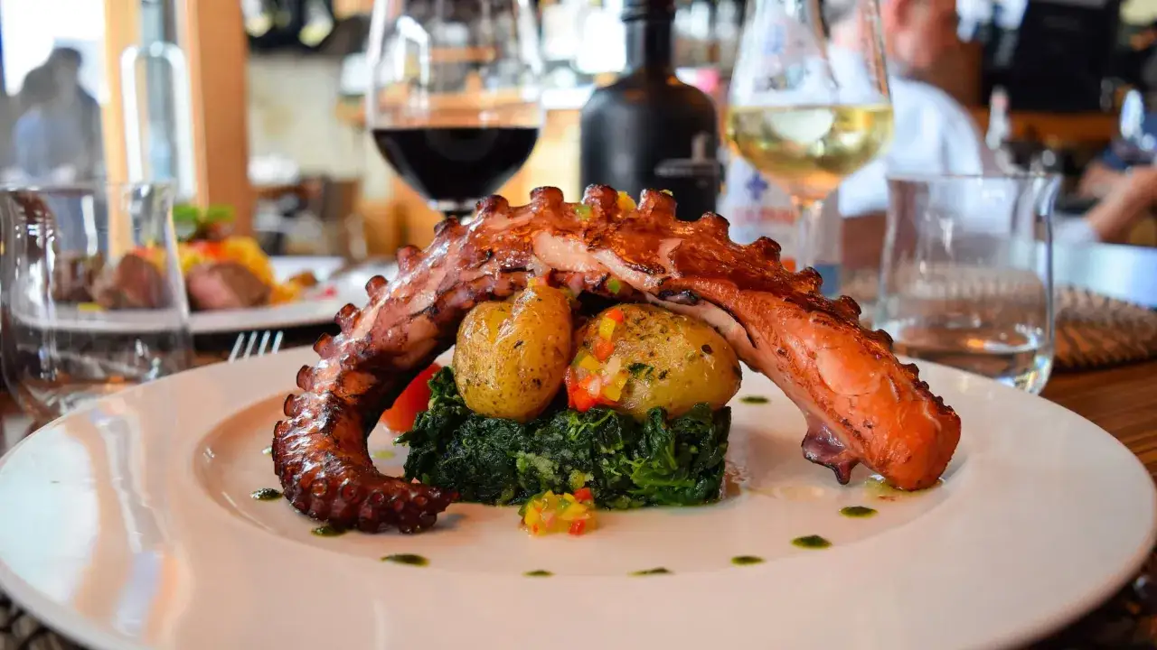 Un plat de poulpe grill&eacute;, pommes de terre et &eacute;pinards, typique d'un restaurant portugais.