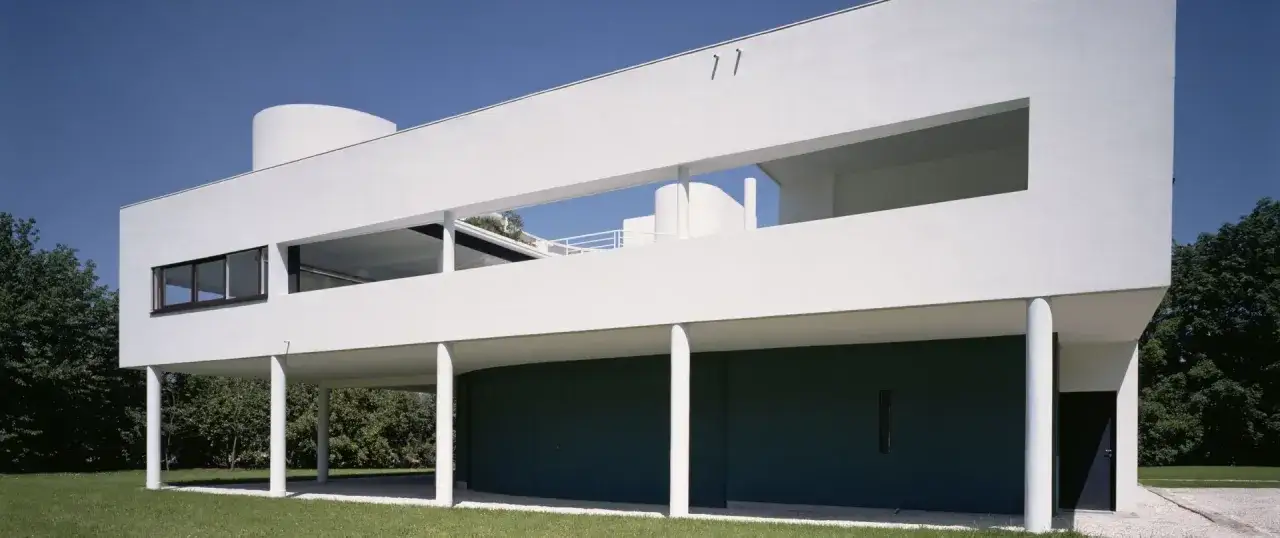 La Villa Savoye, ic&ocirc;ne de l'architecture moderne, se dresse sur pilotis blancs, sa fa&ccedil;ade immacul&eacute;e contrastant avec le ciel bleu et la verdure.
