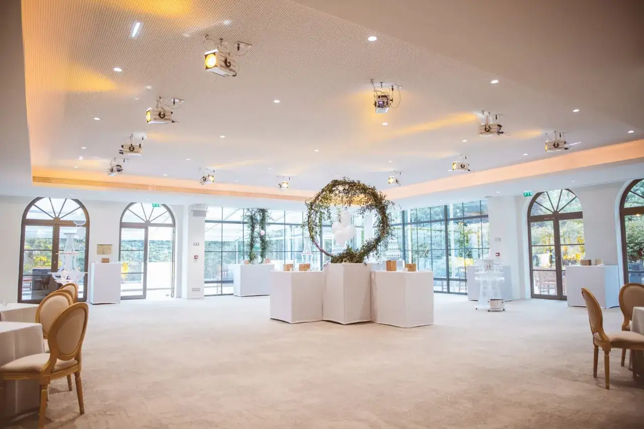 Salle de r&eacute;ception lumineuse au Pavillon Gabriel, d&eacute;cor&eacute;e d'une arche v&eacute;g&eacute;tale et de tables blanches, pr&ecirc;te pour un &eacute;v&eacute;nement.