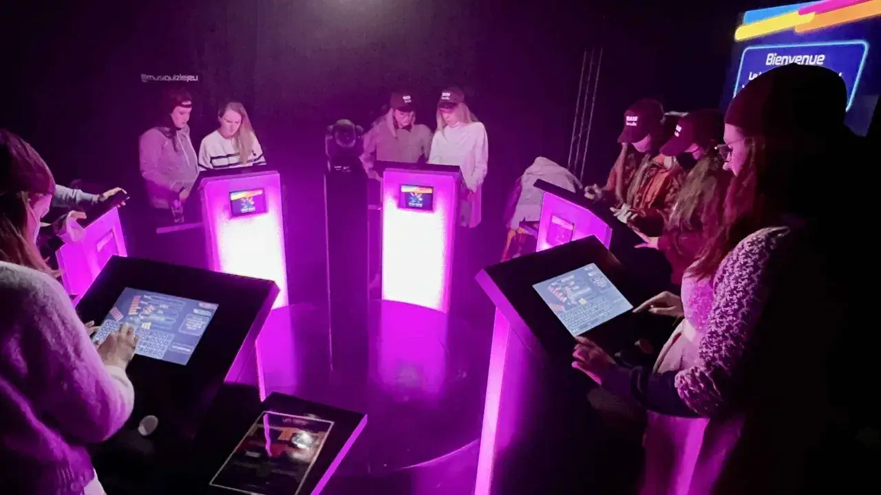 Des jeunes s'affrontent lors d'un blind test musical &agrave; Paris, &eacute;clair&eacute;s par des lumi&egrave;res violettes.