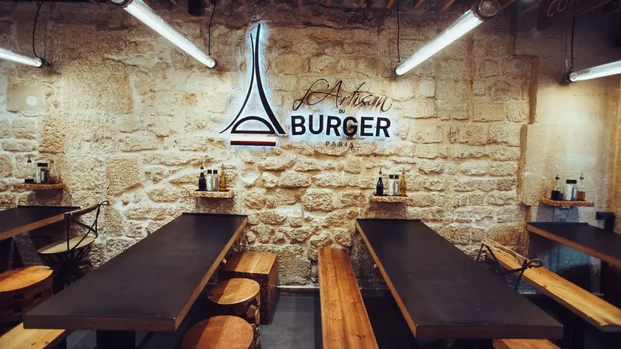 L'Artisan du Burger Paris, un lieu prometteur pour le meilleur burger de Paris. Tables en bois brut, murs en pierre et n&eacute;on stylis&eacute;.
