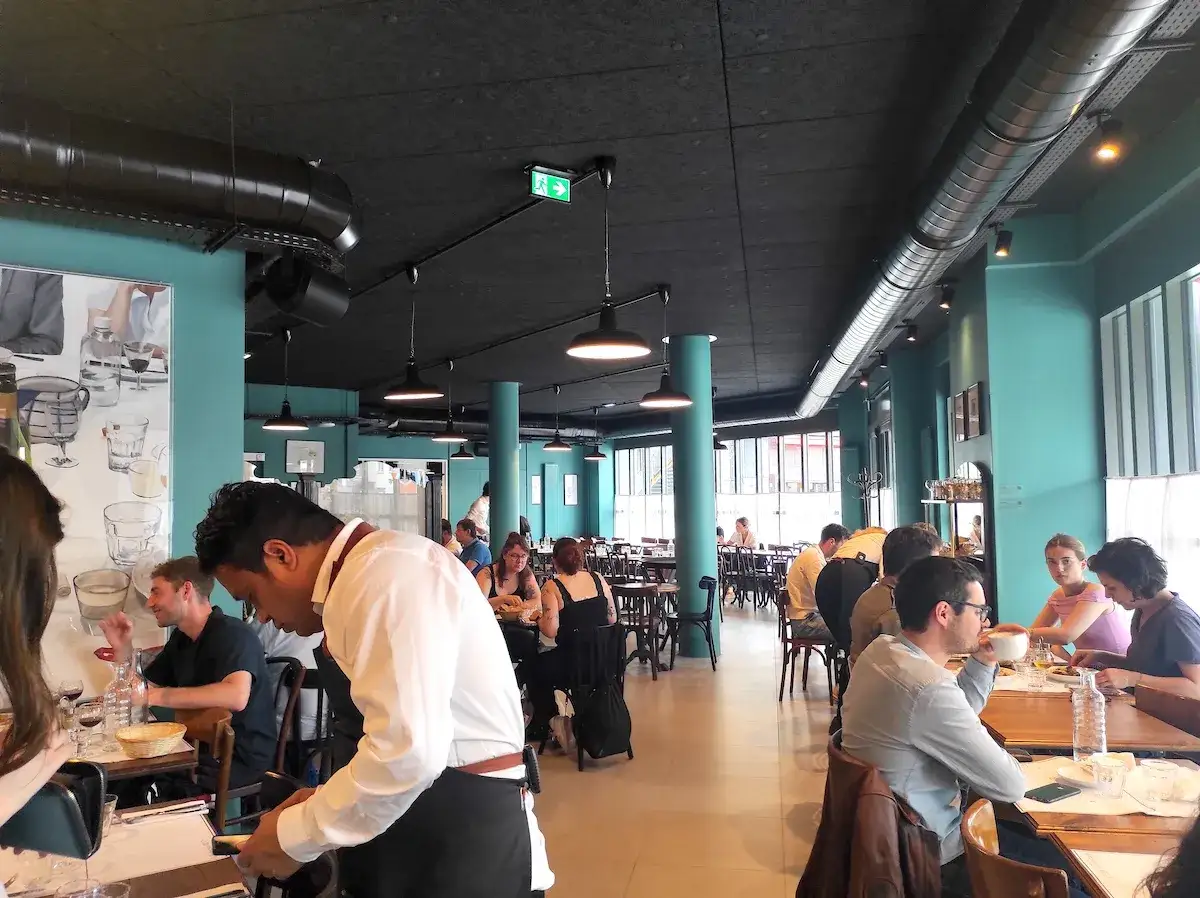 Un restaurant anim&eacute;, des clients attabl&eacute;s savourent un repas, peut-&ecirc;tre le fameux bouillon du coq.