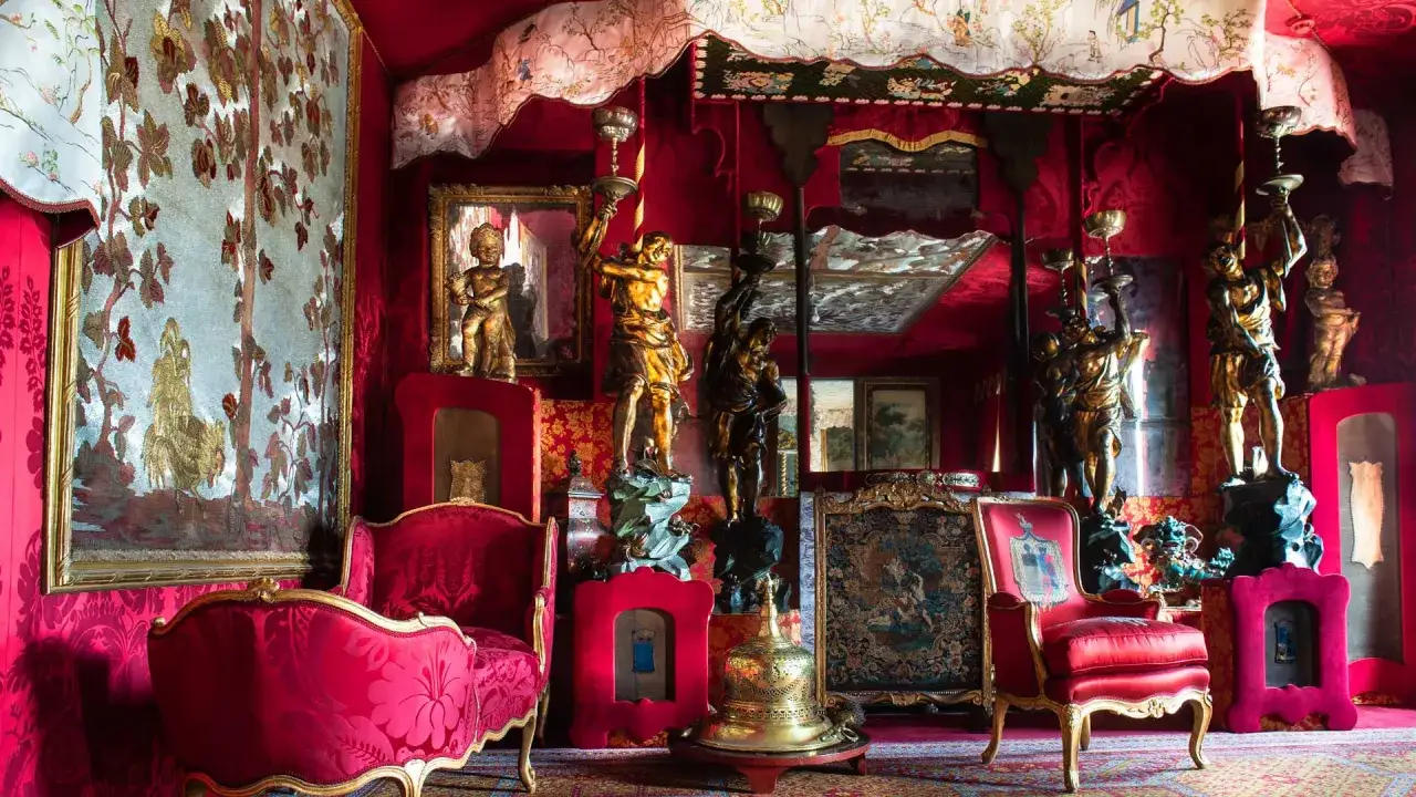 Int&eacute;rieur opulent de la Maison de Victor Hugo &agrave; Paris, avec des fauteuils rouges, des tapisseries et des statues dor&eacute;es.