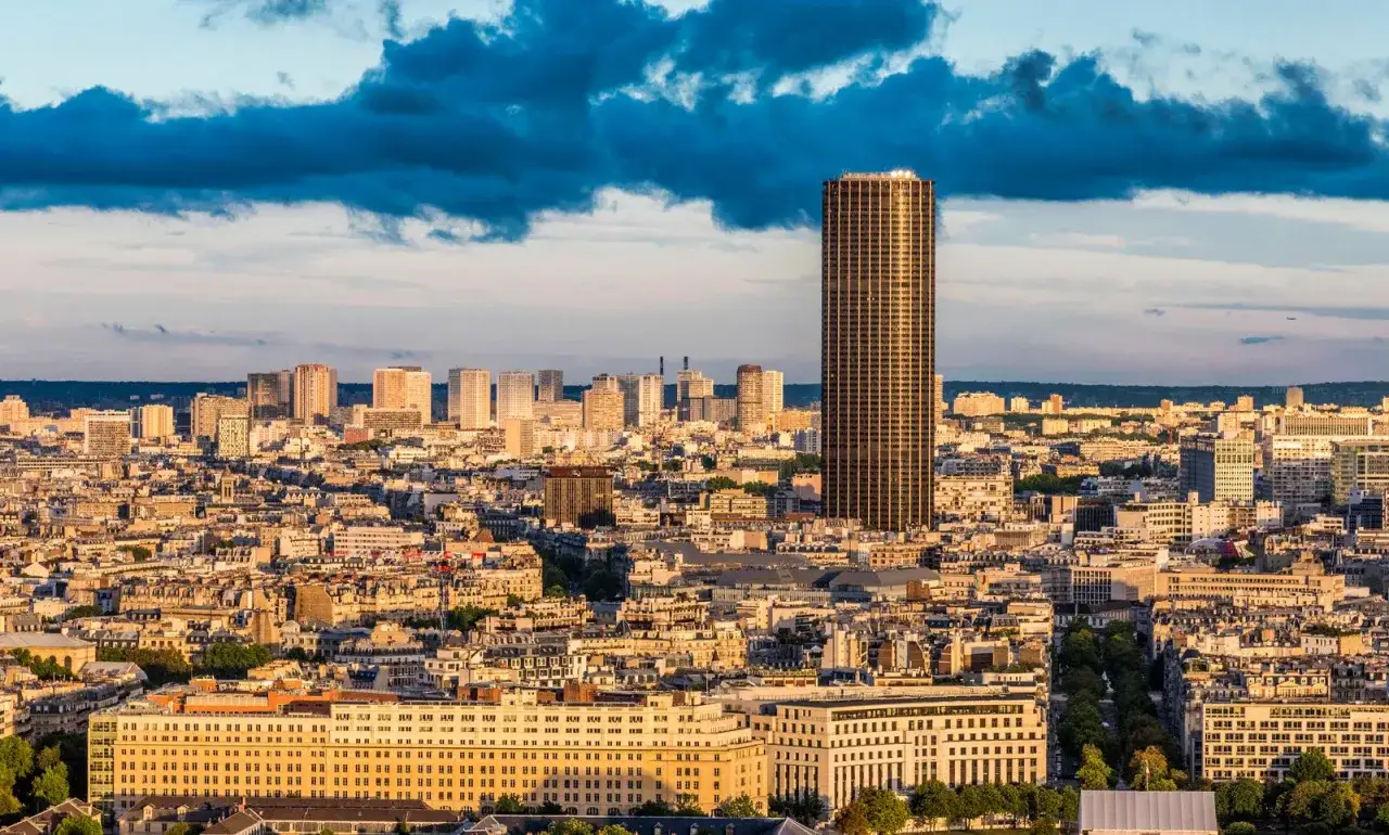 Vue panoramique de Paris depuis le rooftop tour Montparnasse, avec le soleil couchant illuminant la ville.