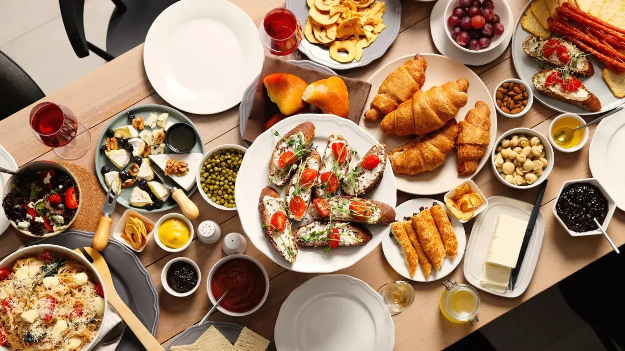 Un festin pour un brunch &agrave; volont&eacute; &agrave; Paris : croissants, toasts, fromages, fruits, p&acirc;tes et accompagnements vari&eacute;s sur une table en bois.