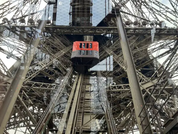 L'ascenseur rouge de la Tour Eiffel monte à travers la structure métallique complexe.