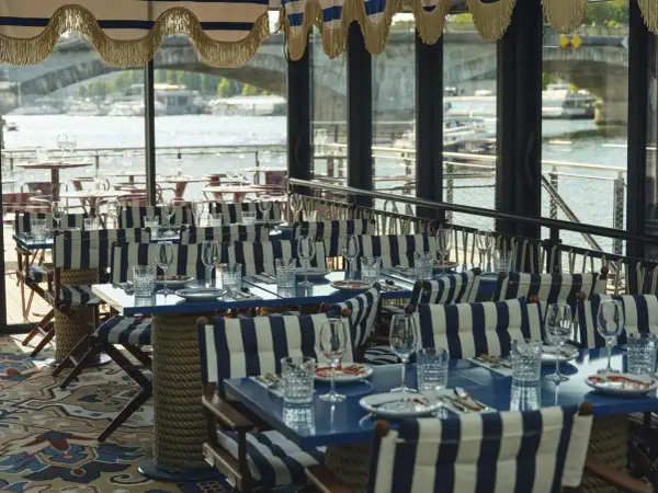 Tables dressées avec des rayures bleues et blanches, prêtes pour une "riviera fuga" sur la Seine.