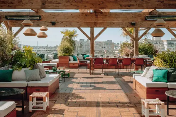 Ambiance chic et verdoyante sur le toit-terrasse du Perchoir Ménilmontant. Canapés confortables, tables dressées et vue panoramique sur Paris.