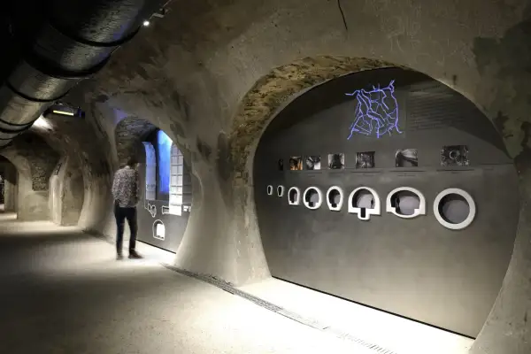 Visite du musée des égouts de Paris. Un visiteur observe une exposition sur le réseau d'assainissement, avec une carte lumineuse et des maquettes.