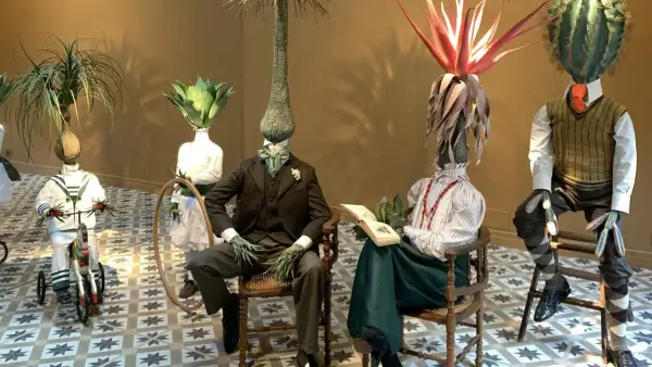 Mannequins aux têtes végétales dans l'espace Monte Cristo. Un enfant sur un tricycle, un couple lisant, un autre debout.