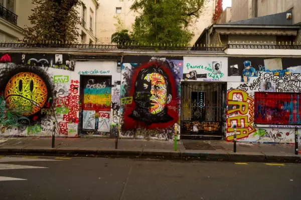 Mur couvert de graffitis colorés devant la maison Gainsbourg, avec un portrait de Serge Gainsbourg au centre.