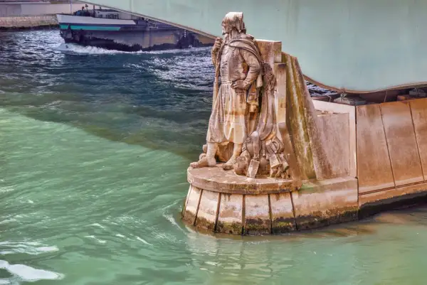 Statue de soldat sur le **pont de l'Alma**, regardant la Seine. Un bateau passe sous le pont.