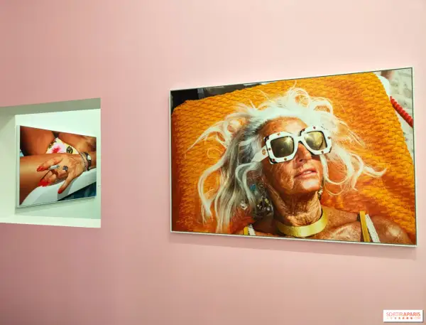 Une femme âgée aux cheveux blancs et lunettes de soleil extravagantes, sur une serviette orange vif. Une autre photo montre une main manucurée tenant une cigarette. Martin Parr expo.