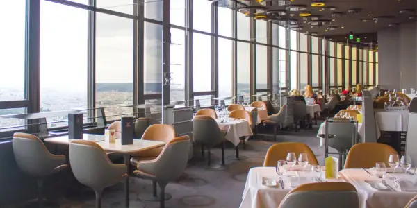 Vue panoramique depuis un restaurant du Tour Montparnasse à Paris. Tables dressées, vue sur la ville.