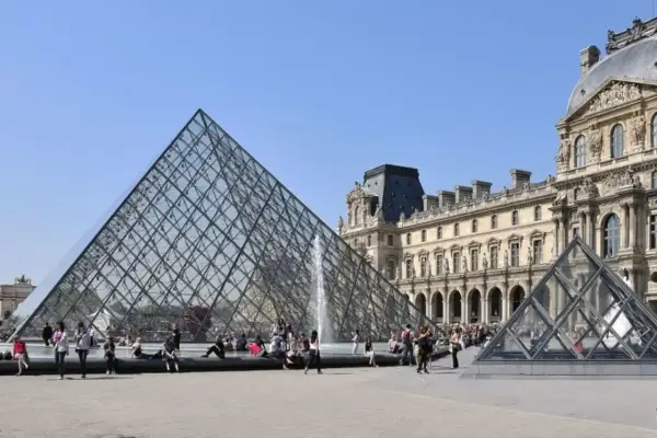 La pyramide du Louvre, un des musées ouverts le lundi, attire des visiteurs sous un ciel bleu.