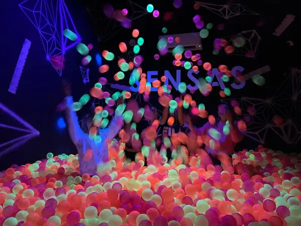 Des balles fluorescentes pleuvent sur des enfants dans une piscine à balles colorée. Une expérience sensas Paris inoubliable.
