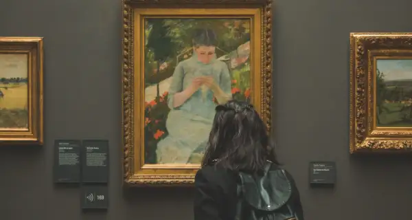 Une visite au musée gratuit premier dimanche du mois. Une jeune femme admire un tableau représentant une jeune fille tricotant dans un jardin.