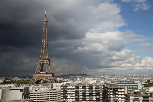 La Tour Eiffel, une des célèbres structures conçues par Gustave Eiffel, se dresse fièrement au-dessus de Paris sous un ciel orageux et lumineux.