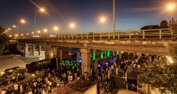 Soirée animée sous un pont, avec une foule dansant et profitant de la musique au Kilomètre 25.