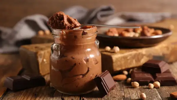 Une cuillère de mousse au chocolat parisienne, onctueuse et gourmande, sur fond de chocolat noir et noisettes.