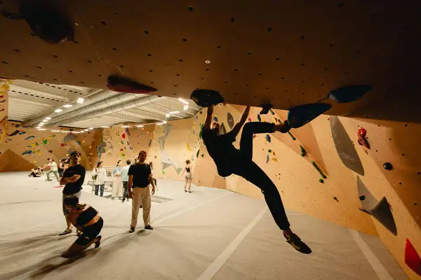 Grimpeurs s'entraînant à l'arkose de Strasbourg Saint-Denis, un mur d'escalade intérieur avec des prises colorées.