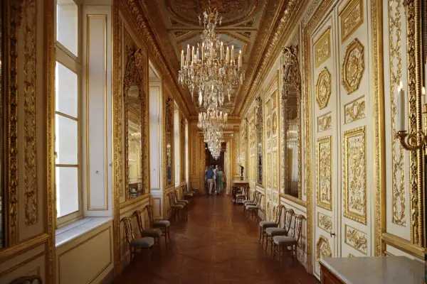 Un long couloir orné de dorures et de lustres étincelants, rappelant la splendeur du **hôtel de la Marine**.