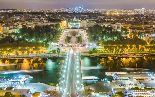 Paris la nuit, le scintillement de la Tour Eiffel se reflète sur la Seine, illuminant la ville.