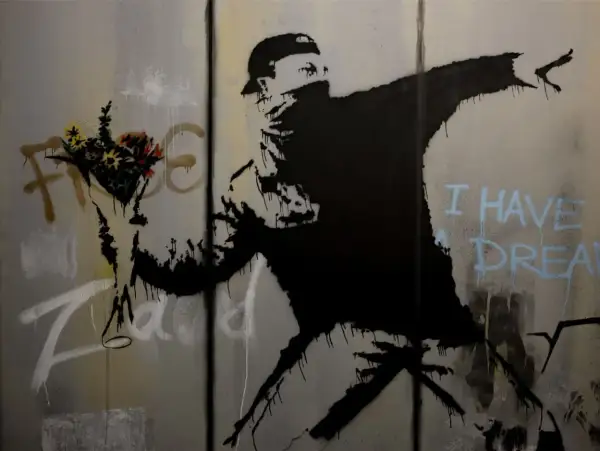 Un homme lance des fleurs, un message d'espoir du musée Banksy Paris. "I have a dream" écrit en bleu.