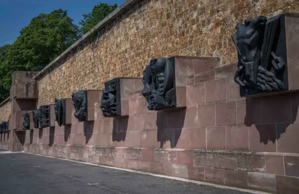 Sculptures sombres sur un mur de pierre à Mont Valérien, évoquant des figures humaines et animales dans un style dramatique.