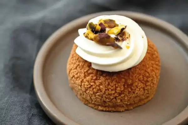 Un délice parisien : un chou craquelin garni de crème onctueuse et parsemé de pistaches concassées.